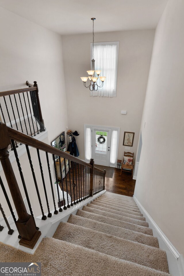 staircase featuring healthy amount of natural light, wood finished floors, a chandelier, and baseboards