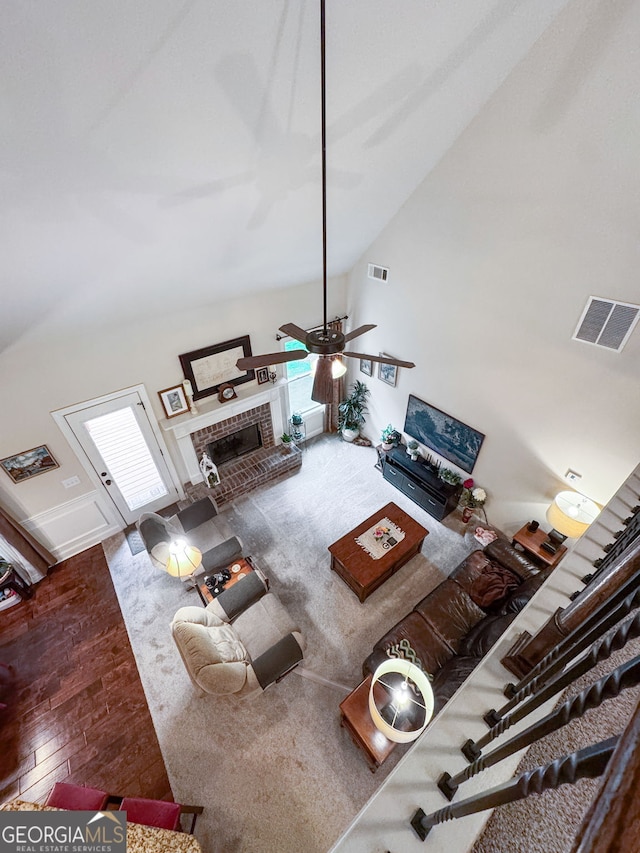 living room with ceiling fan, a fireplace, high vaulted ceiling, and wood finished floors
