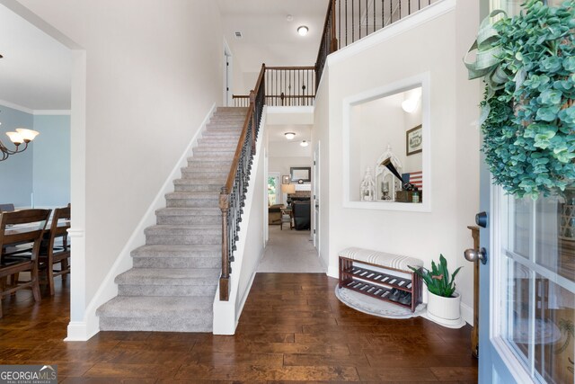 entrance foyer featuring stairway, wood finished floors, a chandelier, baseboards, and a high ceiling