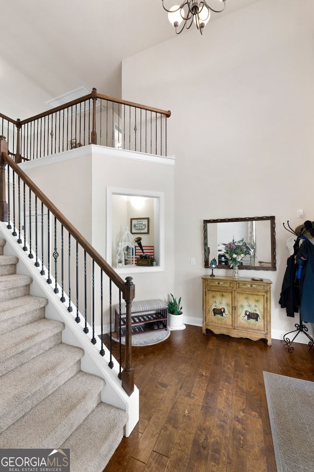 entryway featuring dark wood finished floors, baseboards, a chandelier, stairway, and a towering ceiling