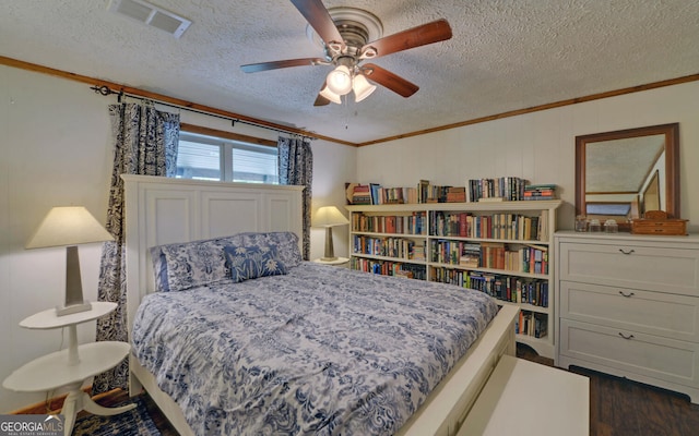 bedroom featuring ornamental molding, a textured ceiling, dark wood-style flooring, and a ceiling fan