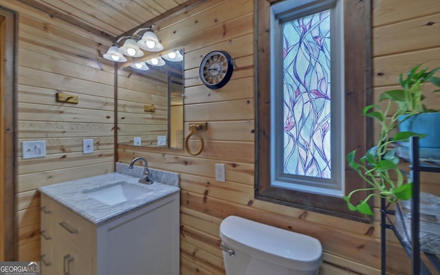 bathroom featuring wood walls, toilet, vanity, and wooden ceiling