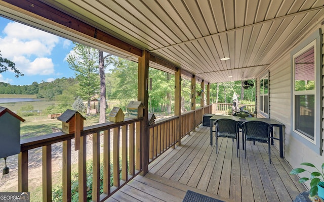 wooden deck with a water view and outdoor dining space