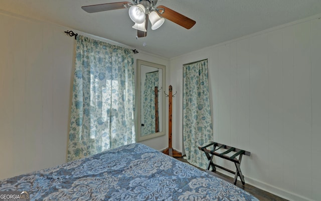 bedroom featuring dark wood-style floors, baseboards, ceiling fan, and crown molding