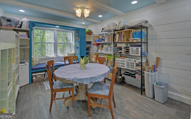dining area featuring wood finished floors, wooden walls, and beamed ceiling