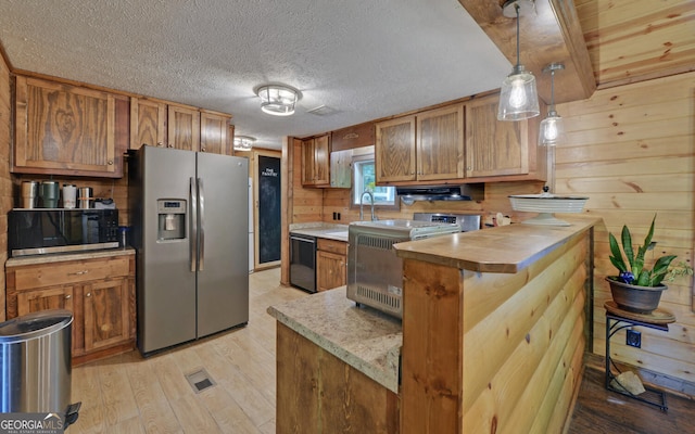 kitchen featuring stainless steel refrigerator with ice dispenser, dishwasher, stove, a sink, and light wood finished floors