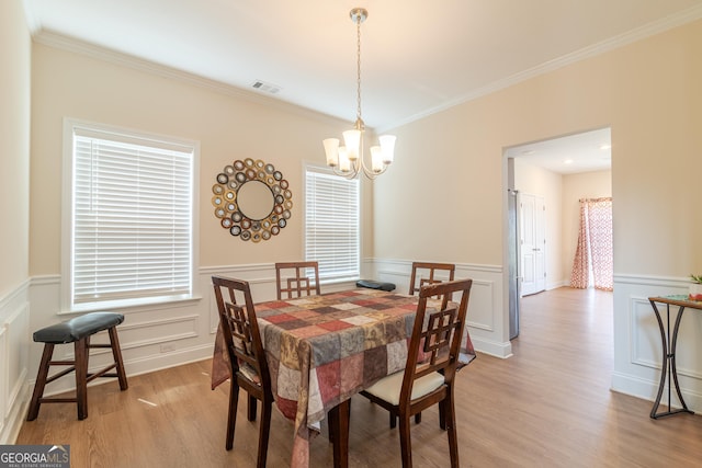 7155 Pine Seed Dr, Midland, GA 31820 - dining area with a chandelier, a wainscoted wall, ornamental molding, light wood-type flooring, and a decorative wall