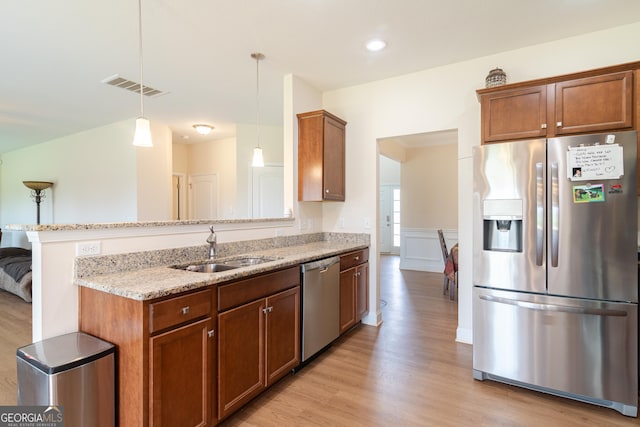 7155 Pine Seed Dr, Midland, GA 31820 - kitchen featuring appliances with stainless steel finishes, a sink, light stone countertops, light wood finished floors, and decorative light fixtures
