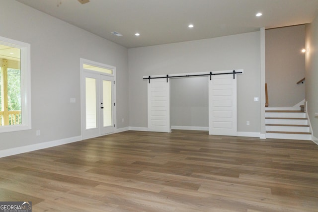 214 Wet Wood Ct Unit 26, Fairburn, GA 30213 - unfurnished living room featuring a barn door, french doors, light wood-style flooring, stairs, and recessed lighting