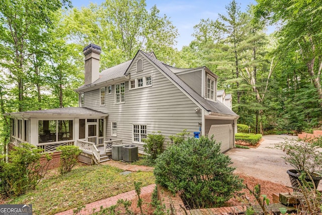 130 River Lndg NE, Sandy Springs, GA 30350 - back of property featuring driveway, a sunroom, a shingled roof, a chimney, and a garage