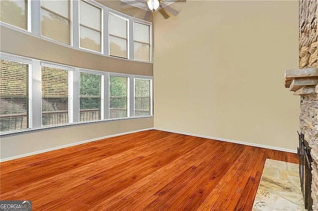 spare room with wood finished floors, a ceiling fan, and baseboards