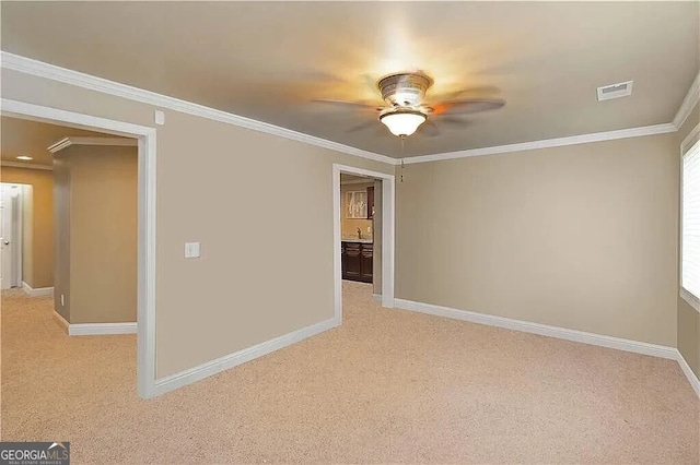 unfurnished room with light colored carpet, ceiling fan, ornamental molding, and baseboards