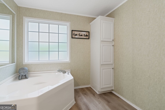 194 Phillips Dr, Eatonton, GA 31024 - bathroom with wood finished floors, crown molding, wallpapered walls, a garden tub, and baseboards