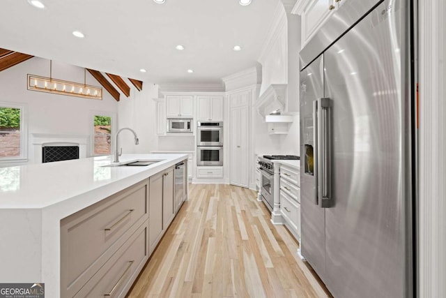 8745 Islesworth Ct, Duluth, GA 30097 - kitchen featuring premium appliances, a sink, light wood-type flooring, white cabinets, and light countertops