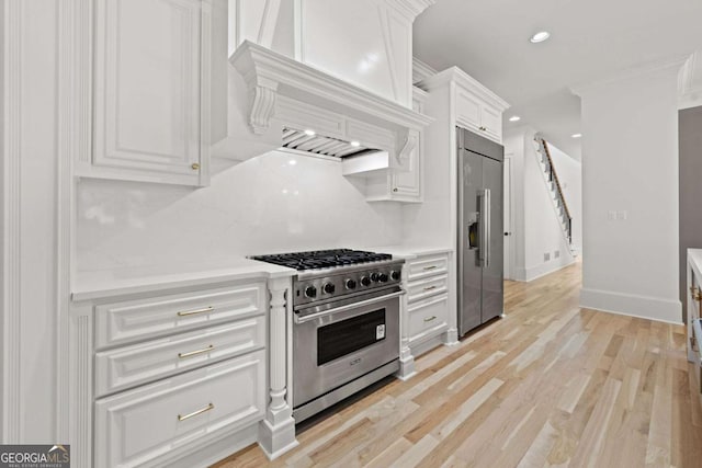 8745 Islesworth Ct, Duluth, GA 30097 - kitchen with premium appliances, white cabinets, light countertops, light wood finished floors, and recessed lighting