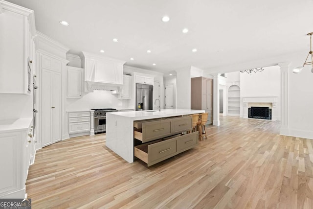8745 Islesworth Ct, Duluth, GA 30097 - kitchen featuring appliances with stainless steel finishes, custom range hood, light wood-type flooring, open floor plan, and light countertops