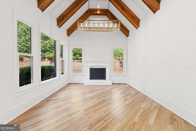 8745 Islesworth Ct, Duluth, GA 30097 - unfurnished living room featuring beamed ceiling, wood finished floors, a fireplace with raised hearth, high vaulted ceiling, and a chandelier