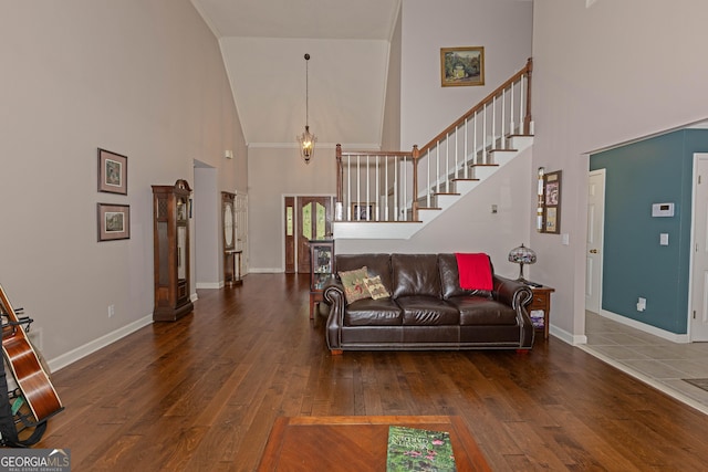 living area with a high ceiling, hardwood / wood-style floors, stairs, and baseboards