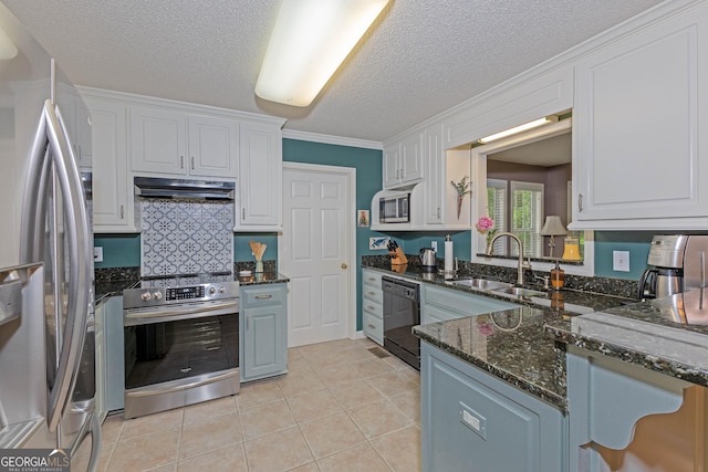 kitchen with appliances with stainless steel finishes, a sink, under cabinet range hood, white cabinetry, and a textured ceiling