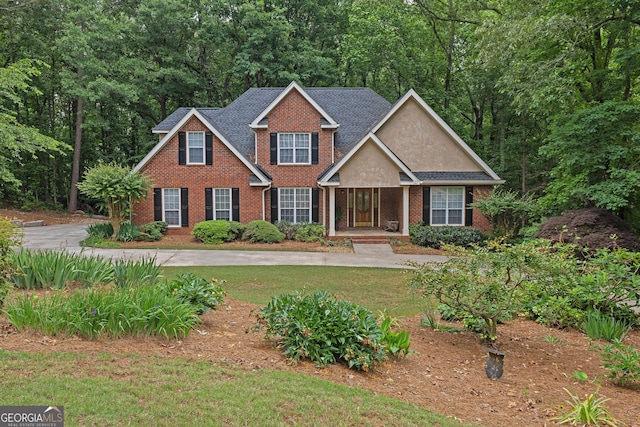 view of front of house with brick siding, a front lawn, and covered porch