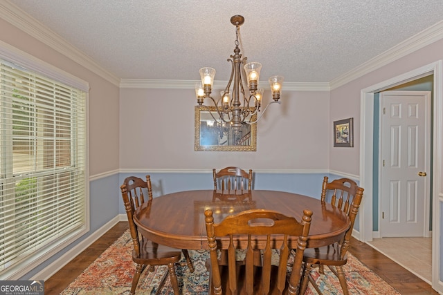 dining area featuring a chandelier, wood finished floors, ornamental molding, a textured ceiling, and baseboards