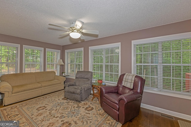 living room featuring baseboards, wood finished floors, a textured ceiling, and a ceiling fan