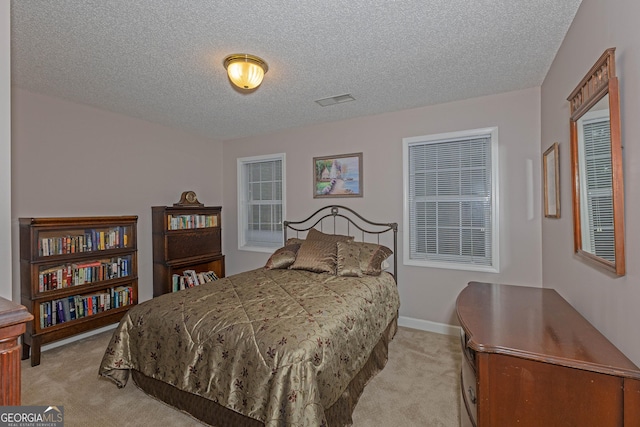 bedroom featuring light carpet, a textured ceiling, and baseboards