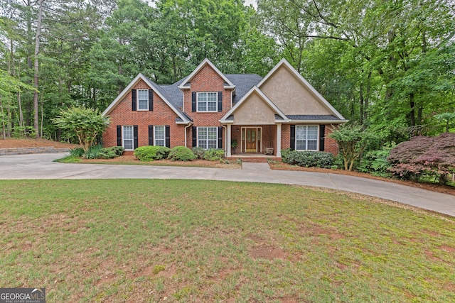 traditional-style home with brick siding, a front yard, covered porch, and driveway