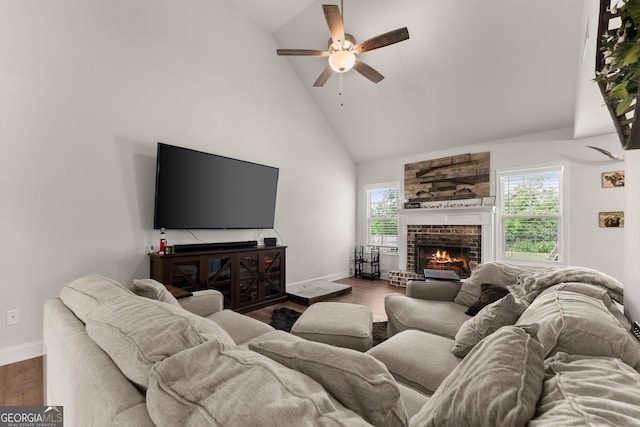 living area featuring high vaulted ceiling, a ceiling fan, baseboards, a fireplace, and plenty of natural light