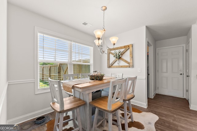 dining area featuring a chandelier, baseboards, and wood finished floors