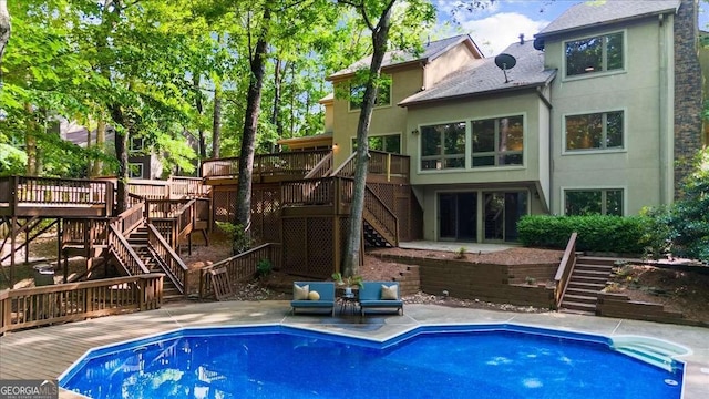 back of property with stairway, a deck, stucco siding, and a patio area