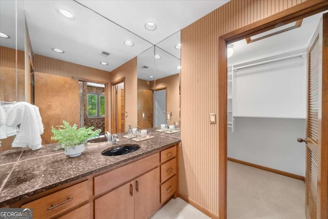 bathroom featuring baseboards, recessed lighting, vanity, wallpapered walls, and a walk in closet