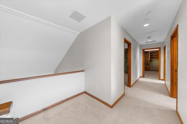 hallway with light carpet, baseboards, and lofted ceiling