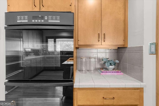 kitchen with tile countertops, backsplash, and wood finished floors