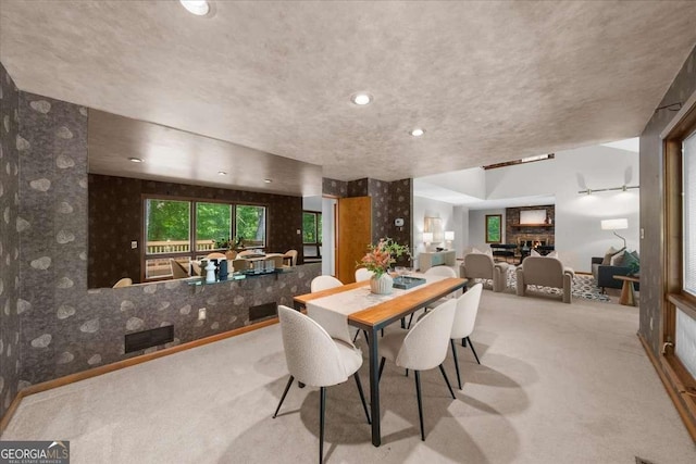 dining area featuring carpet flooring, a textured ceiling, and wallpapered walls