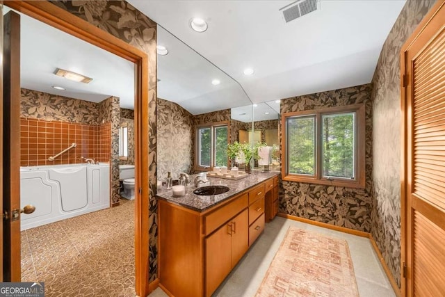 bathroom with toilet, wallpapered walls, vanity, a bathtub, and recessed lighting