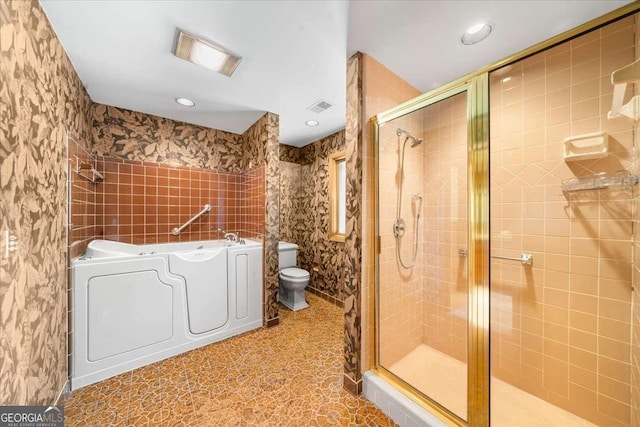 bathroom featuring toilet, a shower stall, a bath, independent washer and dryer, and recessed lighting