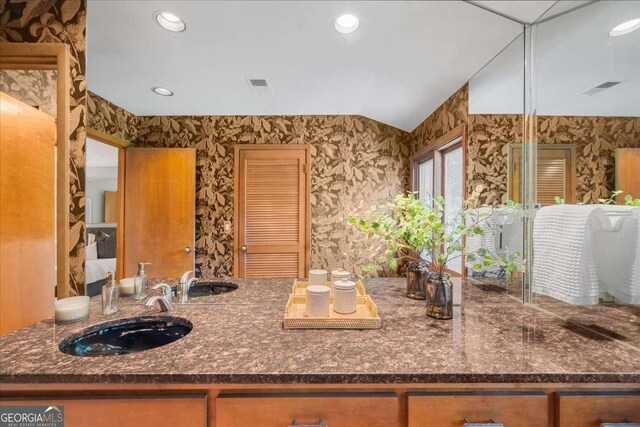 bathroom featuring a sink, wallpapered walls, recessed lighting, and vaulted ceiling