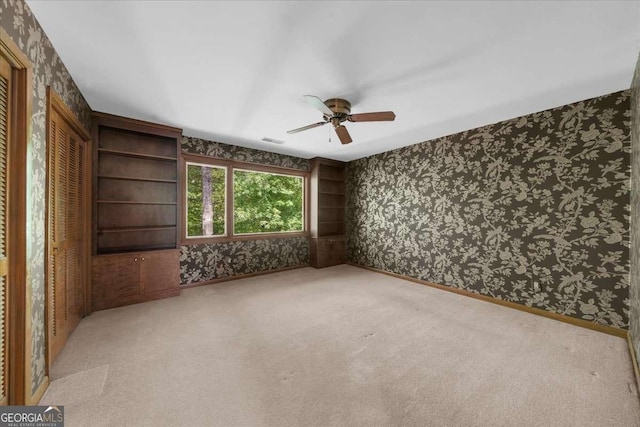 spare room with wallpapered walls, ceiling fan, carpet, and baseboards