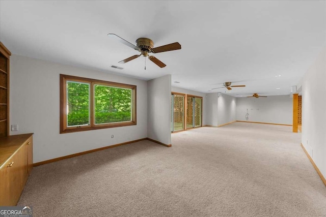 unfurnished living room with a ceiling fan, light colored carpet, and baseboards