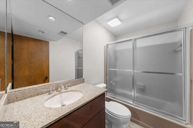 full bath with toilet, vanity, and enclosed tub / shower combo