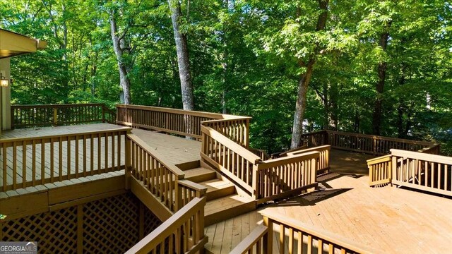 deck featuring stairway and view of wooded area
