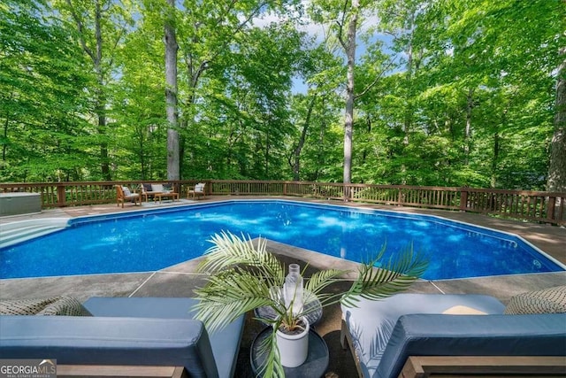 view of pool featuring a deck and view of wooded area