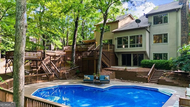 back of house featuring stairs, a deck, stucco siding, and an outdoor pool