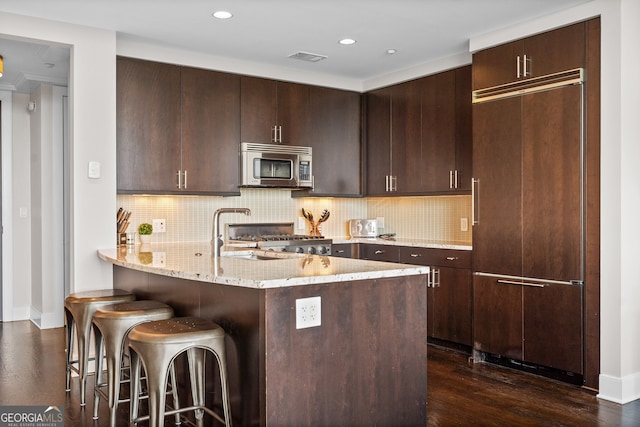 3630 Peachtree Rd NE Unit 1909, Atlanta, GA 30326 - kitchen with stainless steel microwave, a kitchen breakfast bar, stove, light stone counters, and dark brown cabinetry