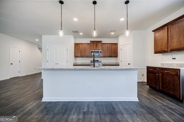 180 Oliver Dr, Locust Grove, GA 30248 - kitchen featuring appliances with stainless steel finishes, dark wood finished floors, backsplash, an island with sink, and recessed lighting