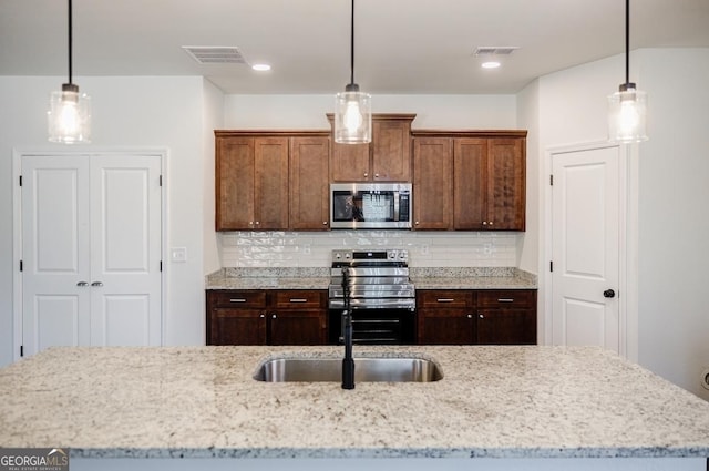 180 Oliver Dr, Locust Grove, GA 30248 - kitchen featuring appliances with stainless steel finishes, tasteful backsplash, light stone counters, and decorative light fixtures