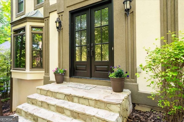 view of exterior entry featuring french doors and stucco siding