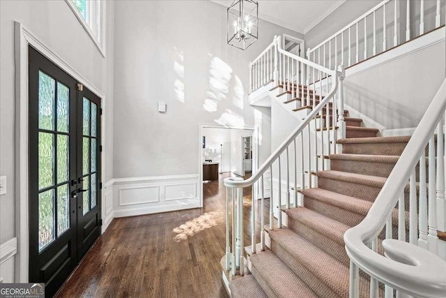 foyer entrance featuring french doors, stairway, dark wood-style floors, a towering ceiling, and ornamental molding