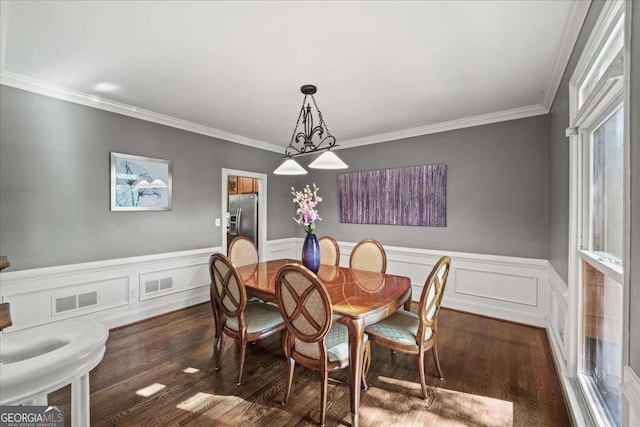 dining area featuring crown molding, dark wood-style flooring, and wainscoting